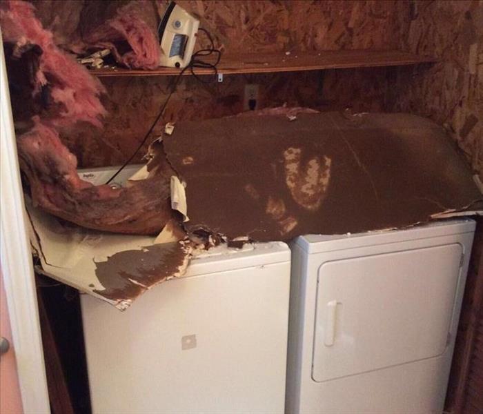 white washer and dryer in closet with drywall, ceiling debris and insulation piled on top