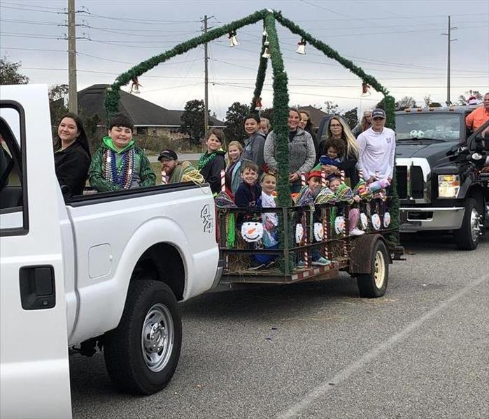 kids and adults in a trailer with christmas decorations being pulled by white pickup