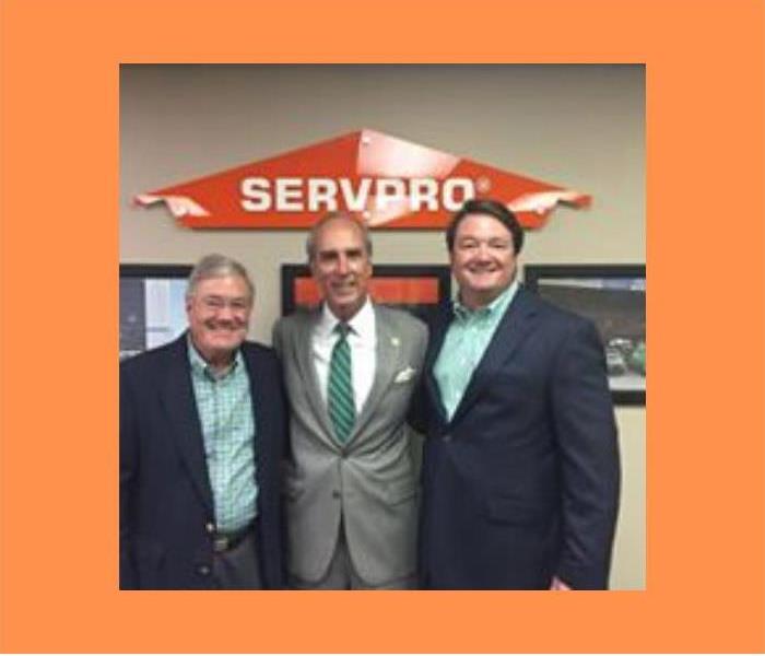 3 men smiling for camera with SERVPRO logo in background