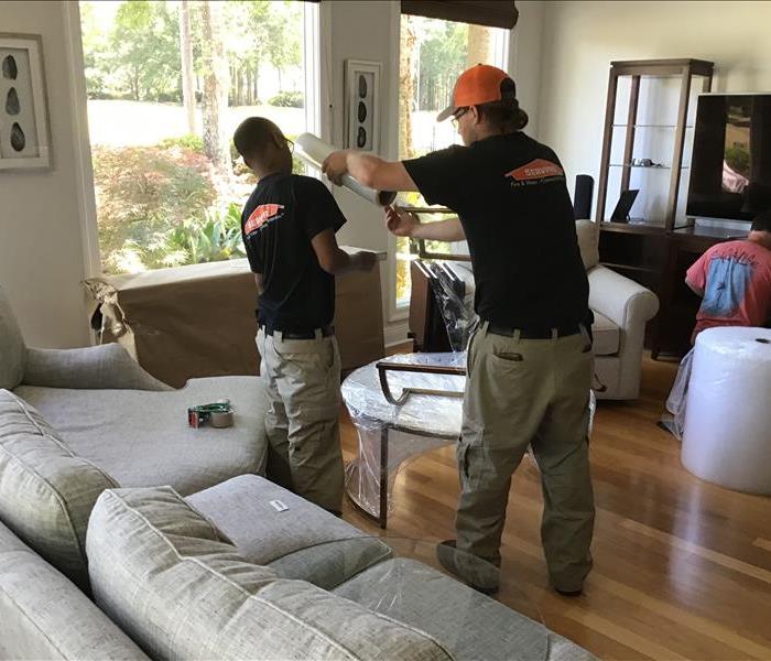 two SERVPRO employees wrapping tables in bubble wrap