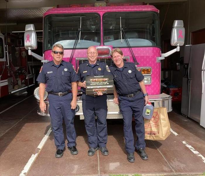 3 Firefighters standing in front of a pink fire truck