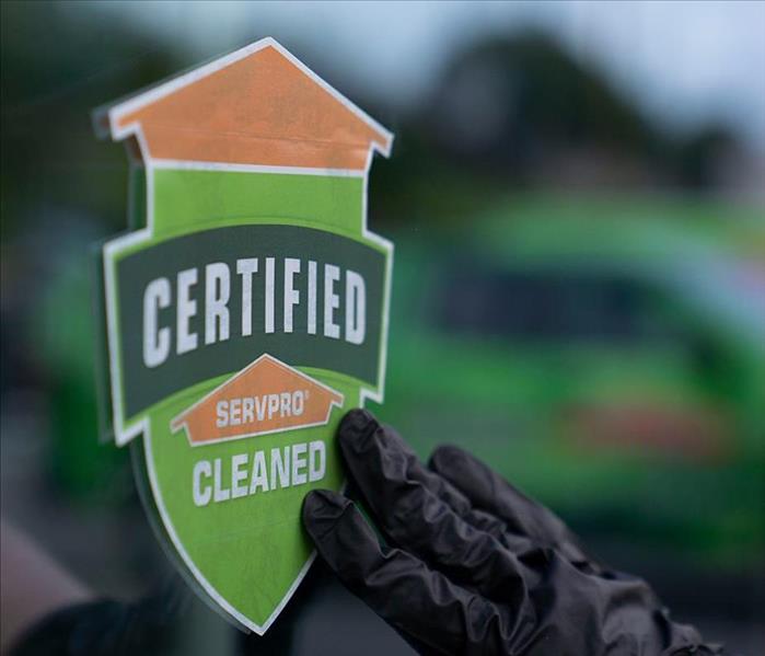Certified: SERVPRO Cleaned window cling being applied by hand with black glove on. 