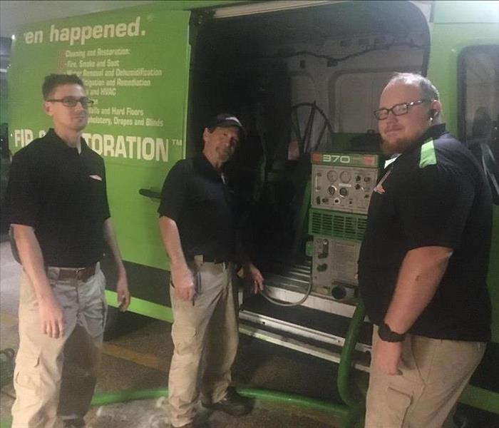 3 men standing in front of green van smiling for camera
