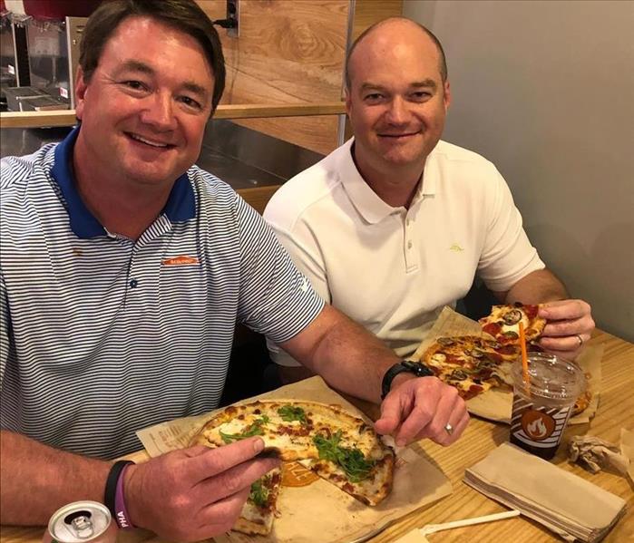 two men sitting for dinner of pizza
