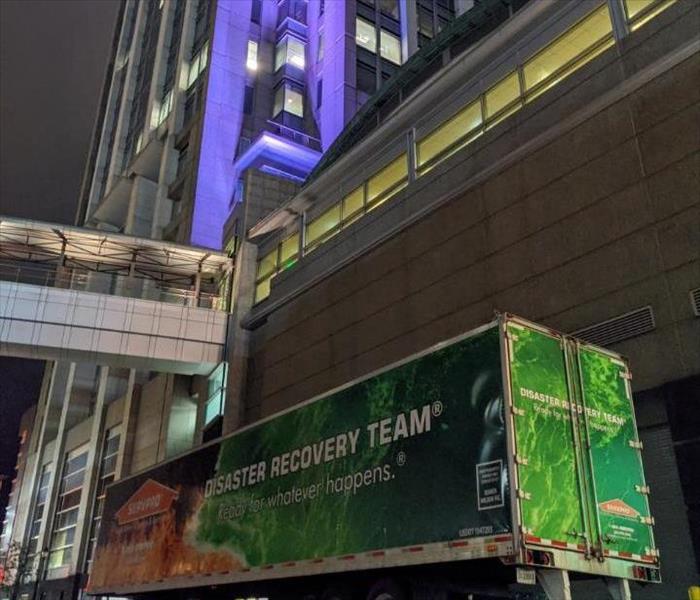 Tall Building with purple lighting and SERVPRO Storm Truck parked in front